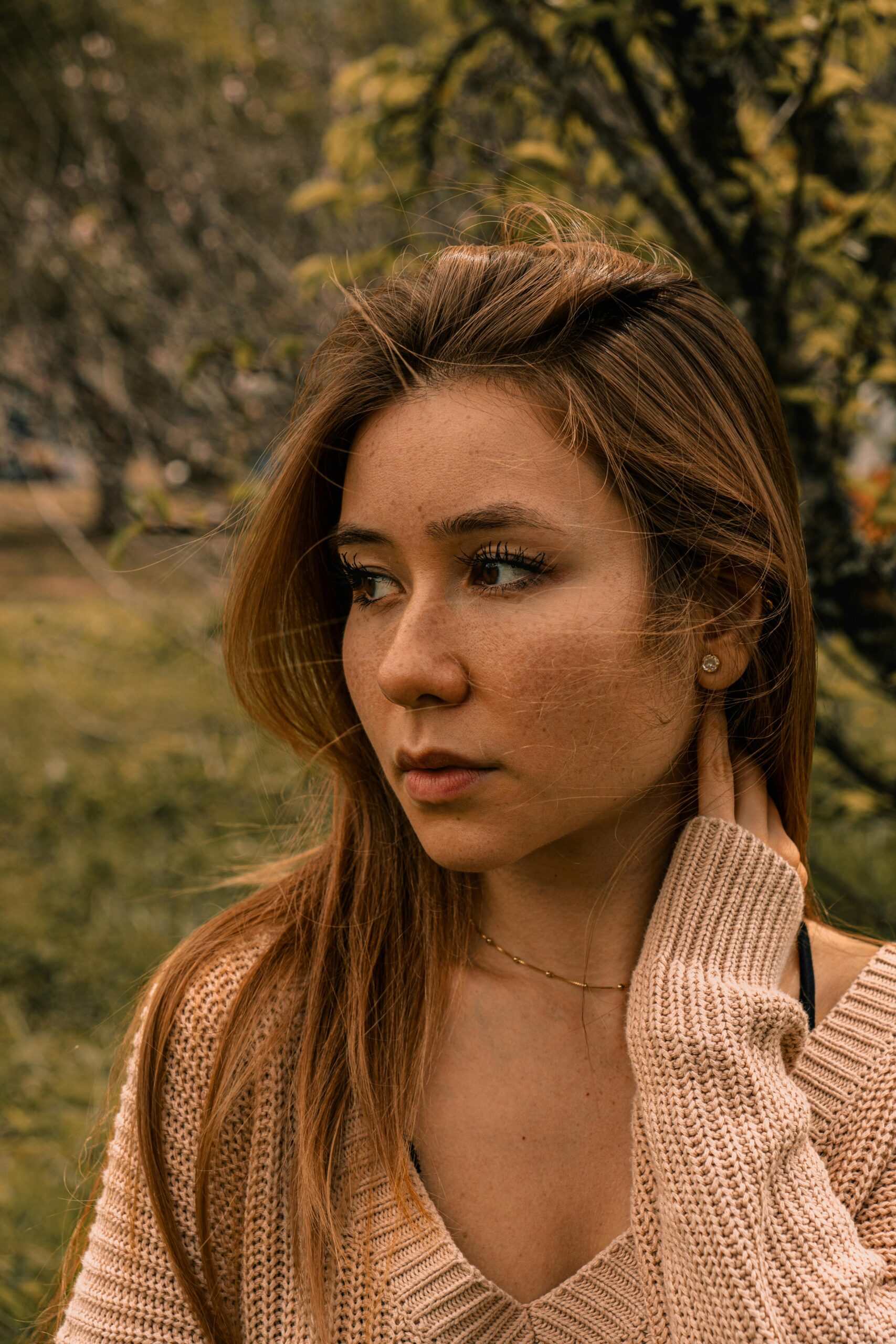 Portrait of a young woman with brown hair enjoying a peaceful moment outdoors.